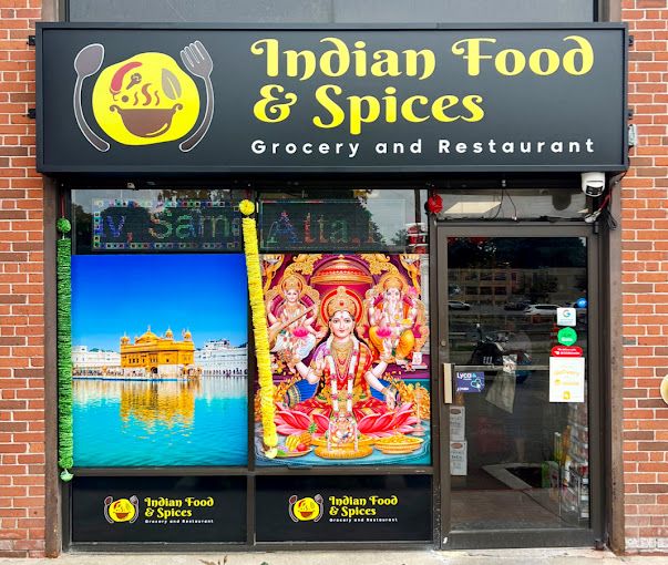 The Indian Food and Spices storefront with its yellow and black sign reading Grocery and Restaurant